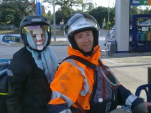 two people on a motorcycle. the person on the back has bandages on her face.