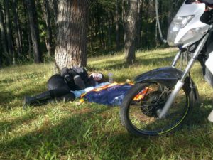 Lady laying on the ground with a motorcycle in the forefront