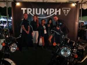 Group of people with a Triumph motorcycle sign