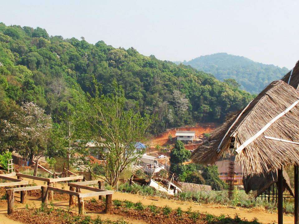 a thatched roof and a fence in a forest Mon Jam