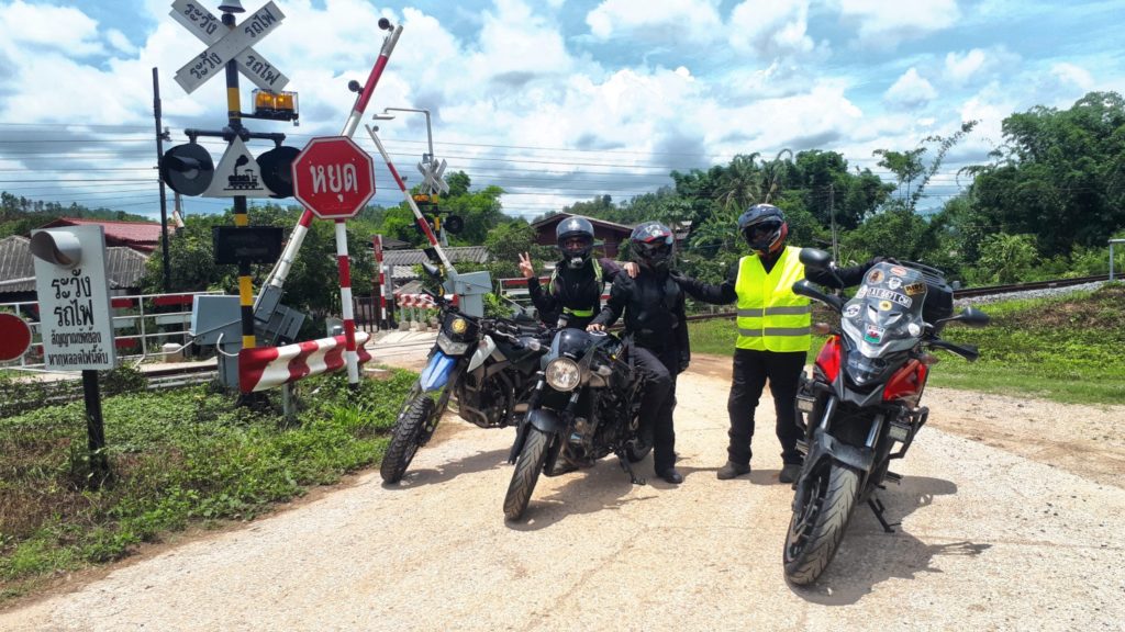 motorcycles parked at a railway crossing and lady motorbike riders in Thailand