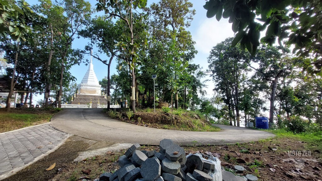 a white temple chedi and sweeping tight curvy road with green trees and a blue sky in Chiang Mai, Thailand