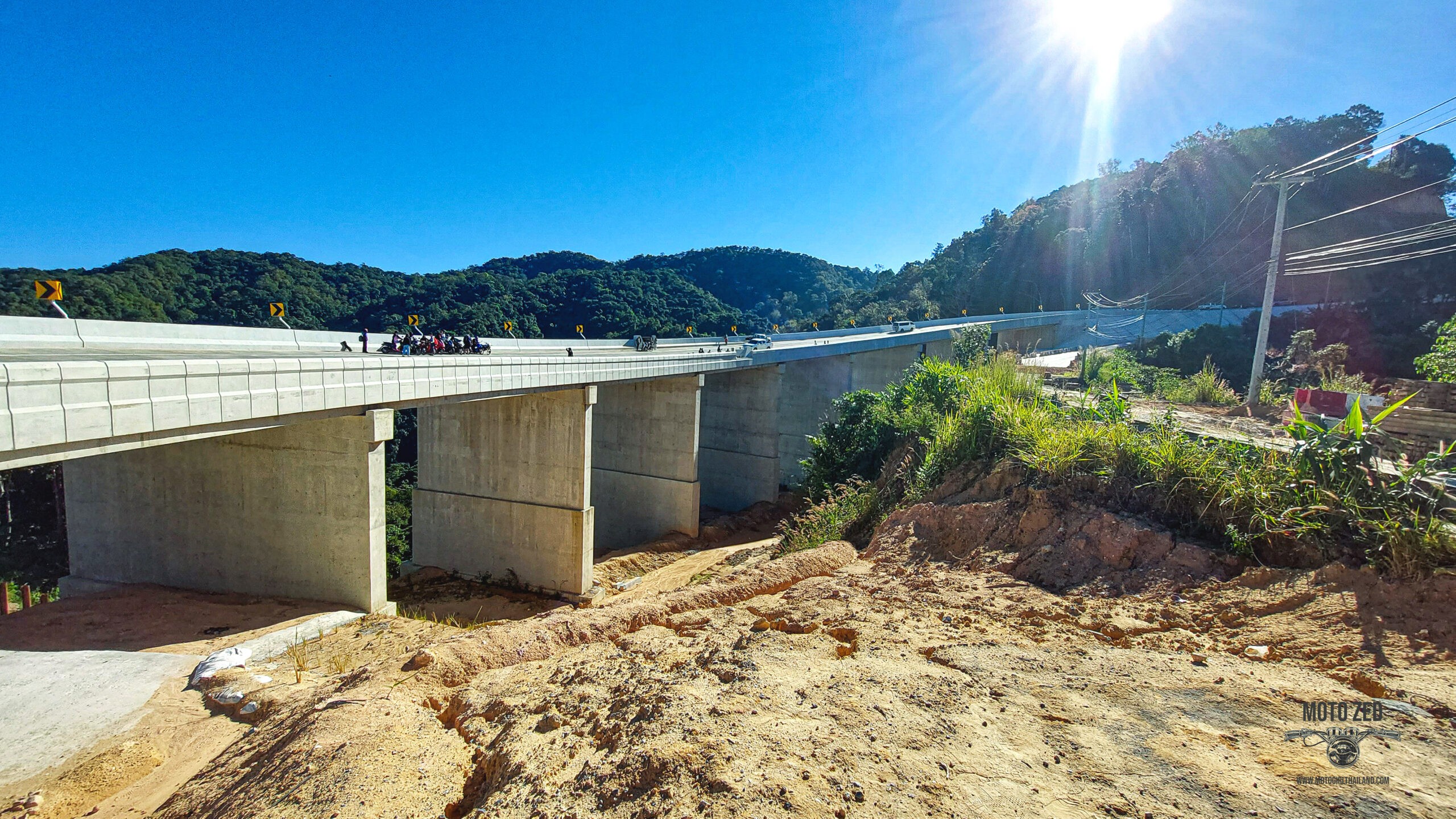 new bridge construction from the distance. The people are very small and it is set in a mountain landscape. Kew Lom Bridge, Khun Yuam.