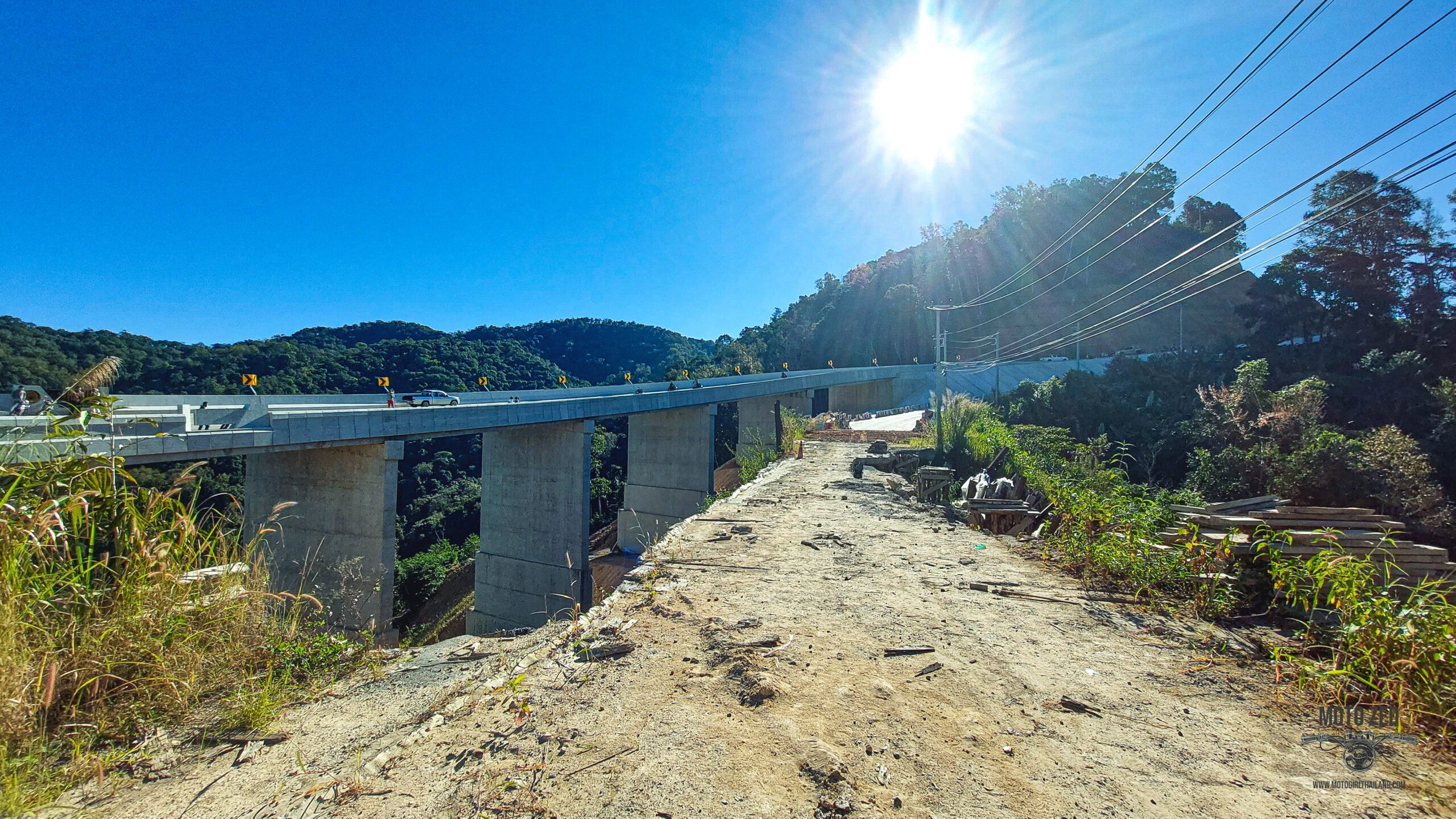 new bridge construction from the distance. The people are very small and it is set in a mountain landscape