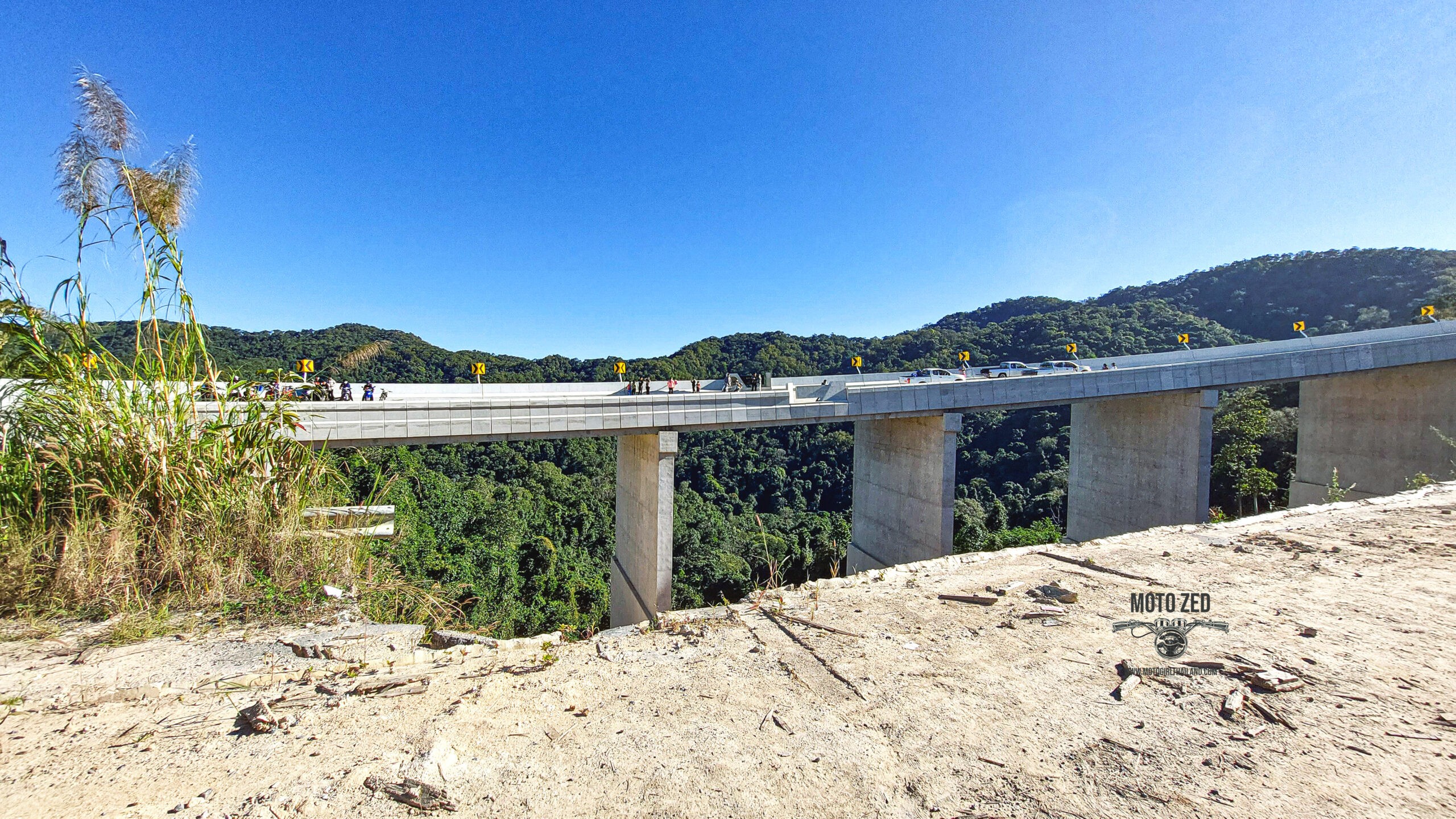 new bridge construction from the distance. The people are very small and it is set in a mountain landscape