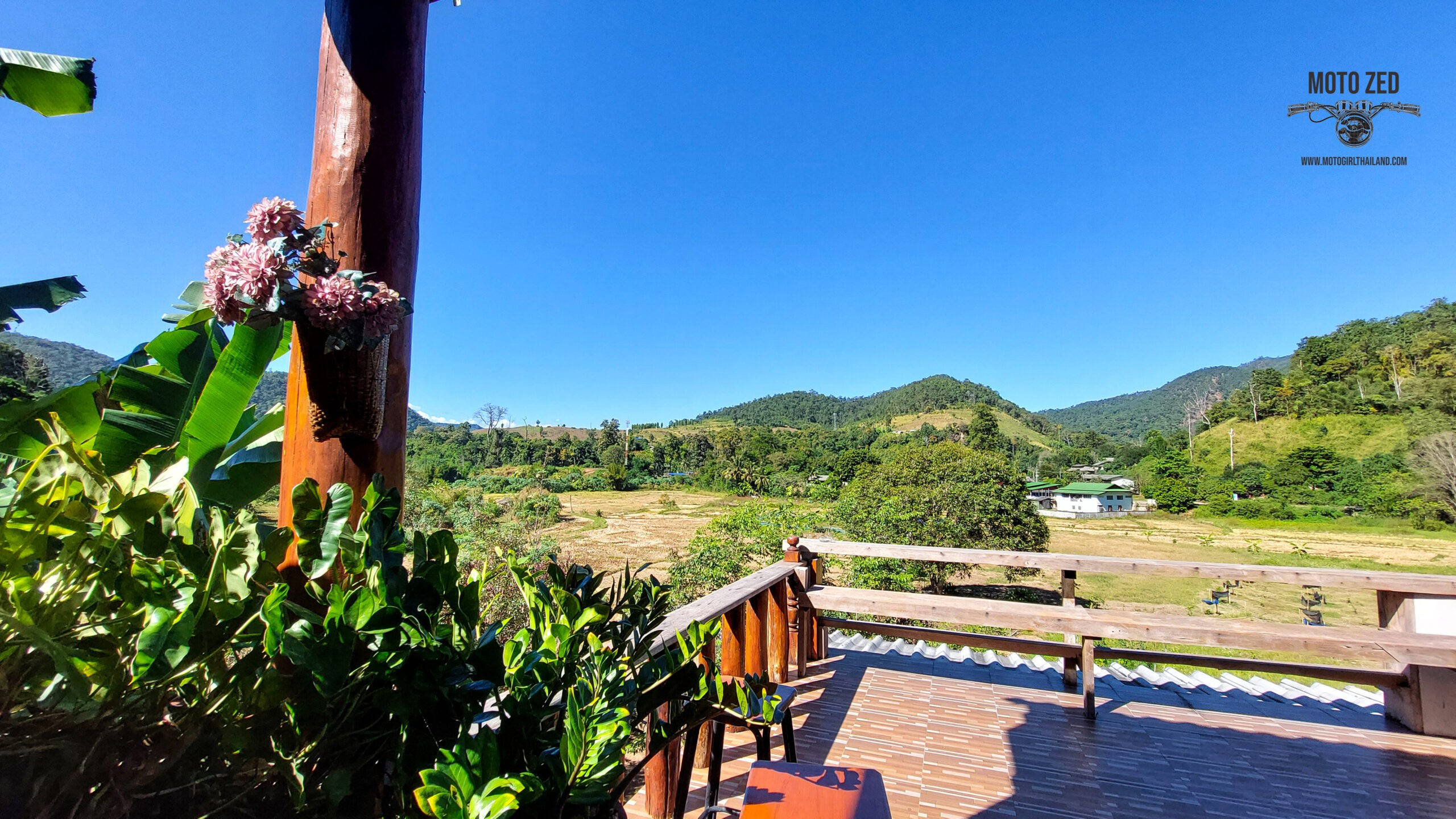 mountain landscape view from a deck area. Sunlight is shining and the sky is blue.