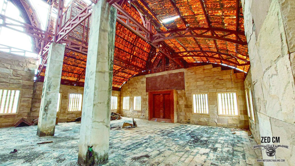 Inside an abandoned building with moss growing. The light is spilling through the roof which has holes, lighting up the inside of the building