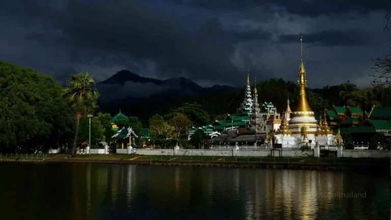a golden temple on a lake at night